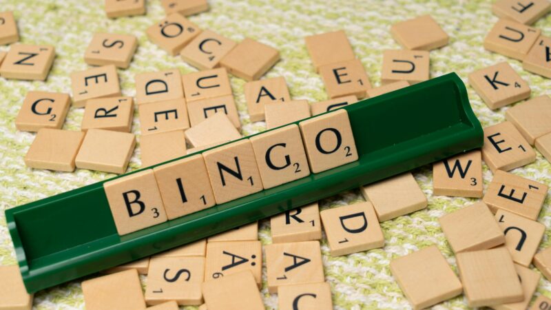 Wooden Scrabble tiles arranged to spell 'BINGO' on a green rack.